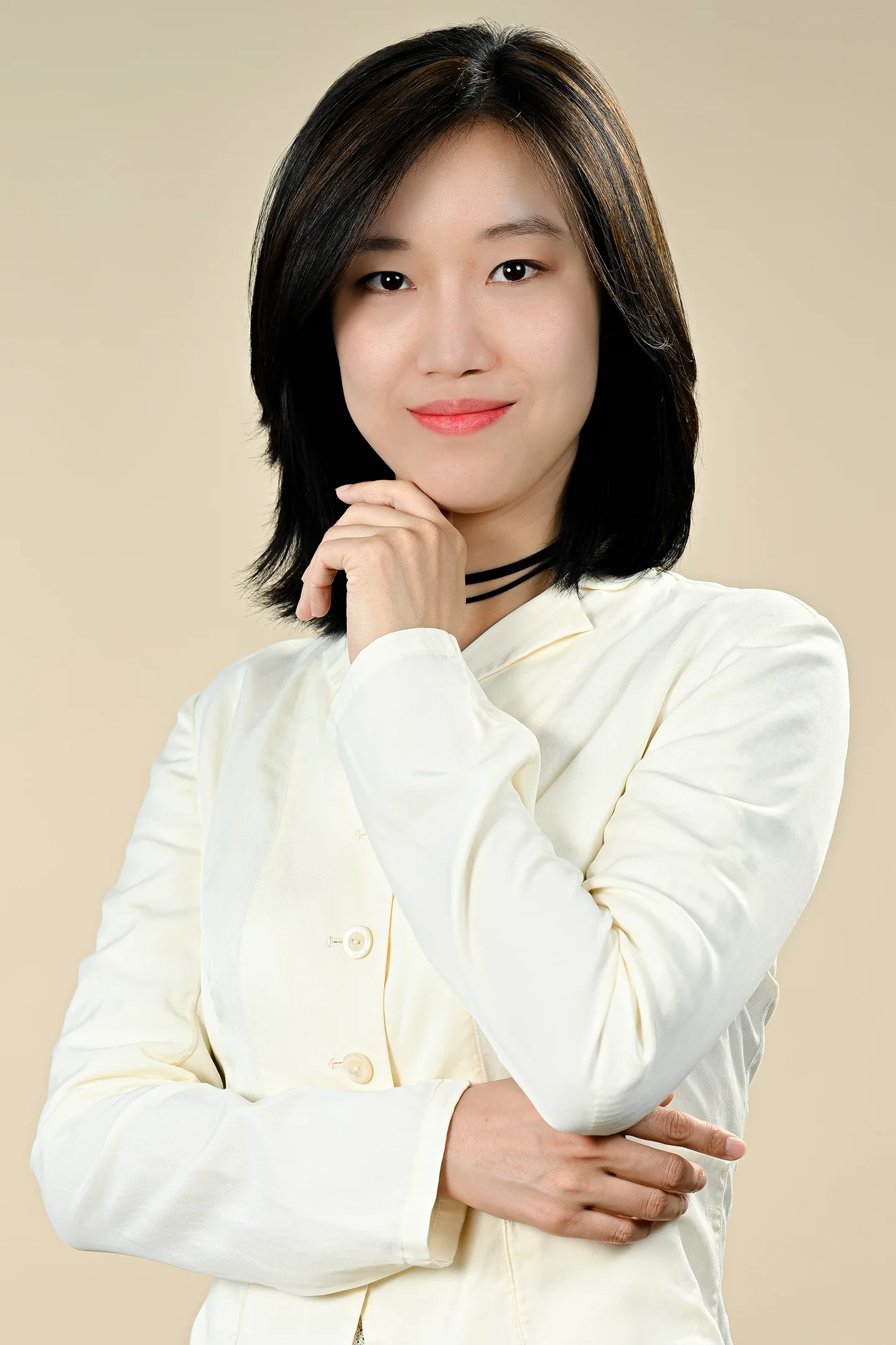 Corporate portrait of woman wearing a white blazer in the studio against a cream backdrop